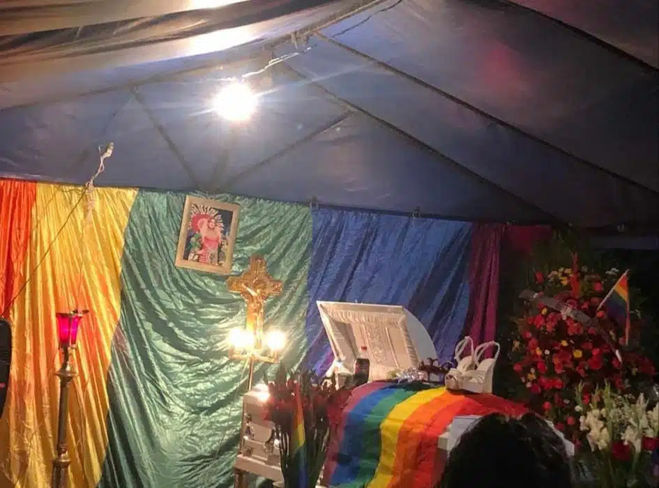 Flores rojas y blancas, la bandera de la comunidad LGBT+ y tacones blancos cubren el ataúd de Juventino