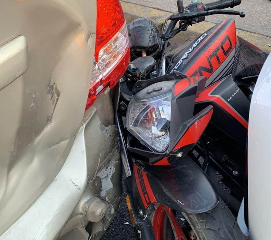 Motocicleta atorada entre dos vehículos