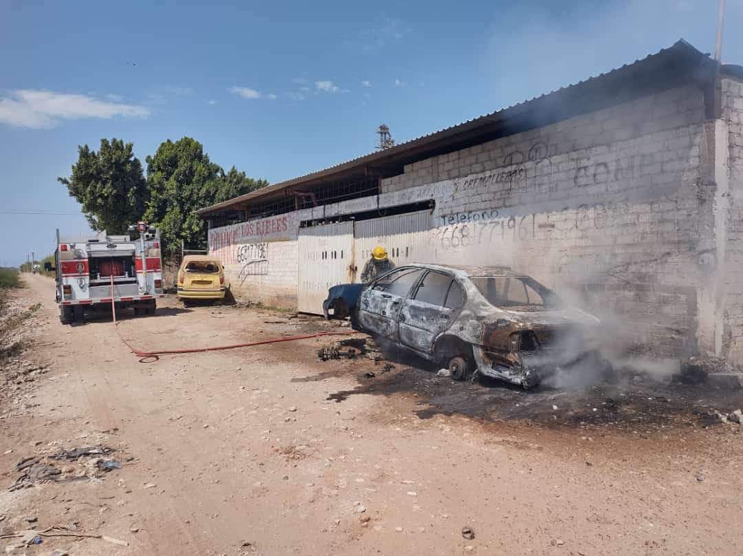 Vehículo quemado, con humo saliendo de éste a las afueras de un yonke