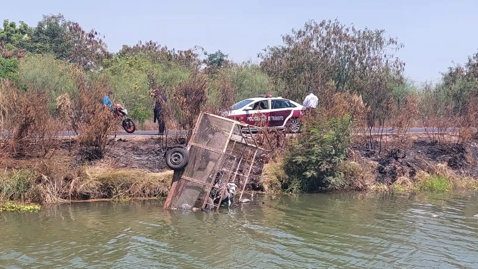 Remolque cargado de basura al interior de un canal. Hay presencia de la Policía Municipal