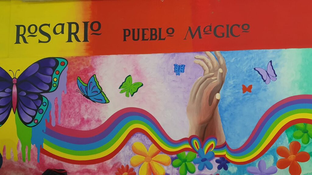 Mural con diversos dibujos y colores de arcoíris donde pueden verse manos, flores y una mariposa