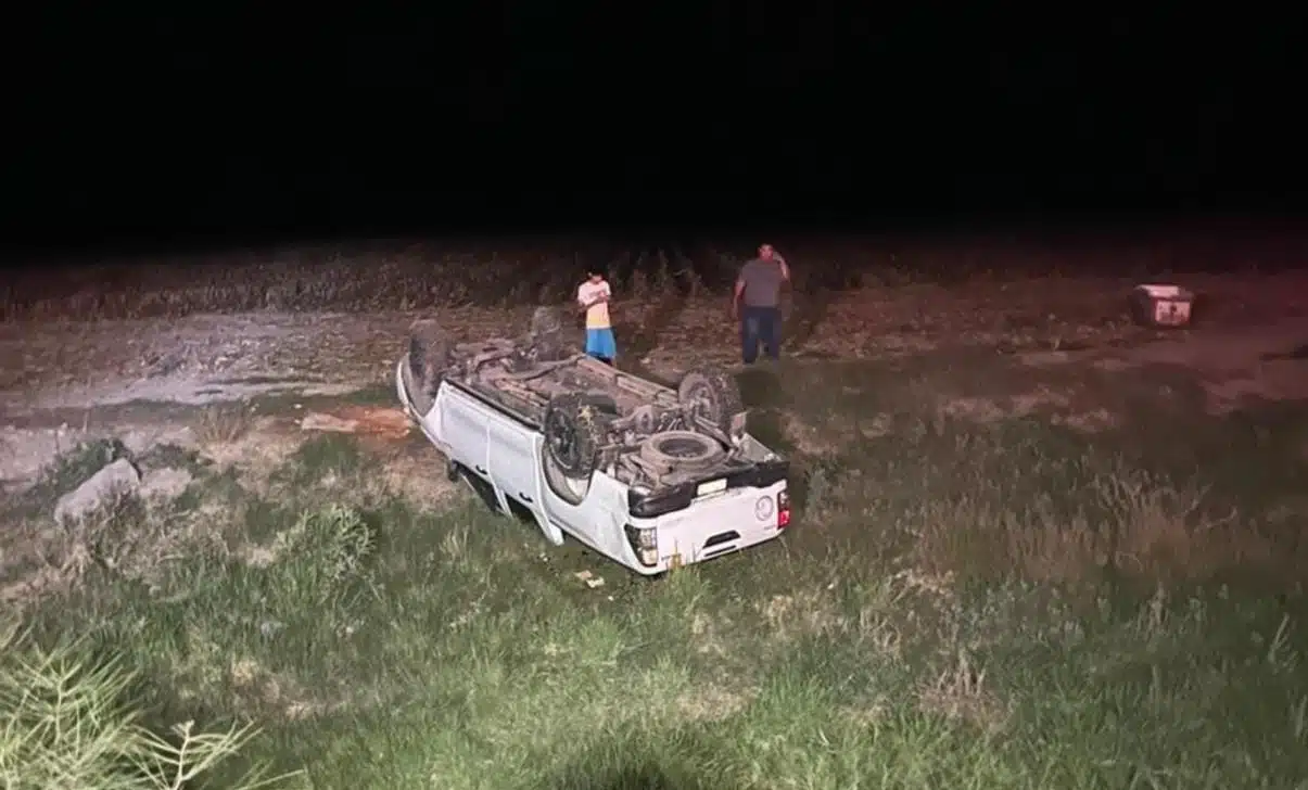 2 personas mirando una camioneta con los neumáticos hacia arriba