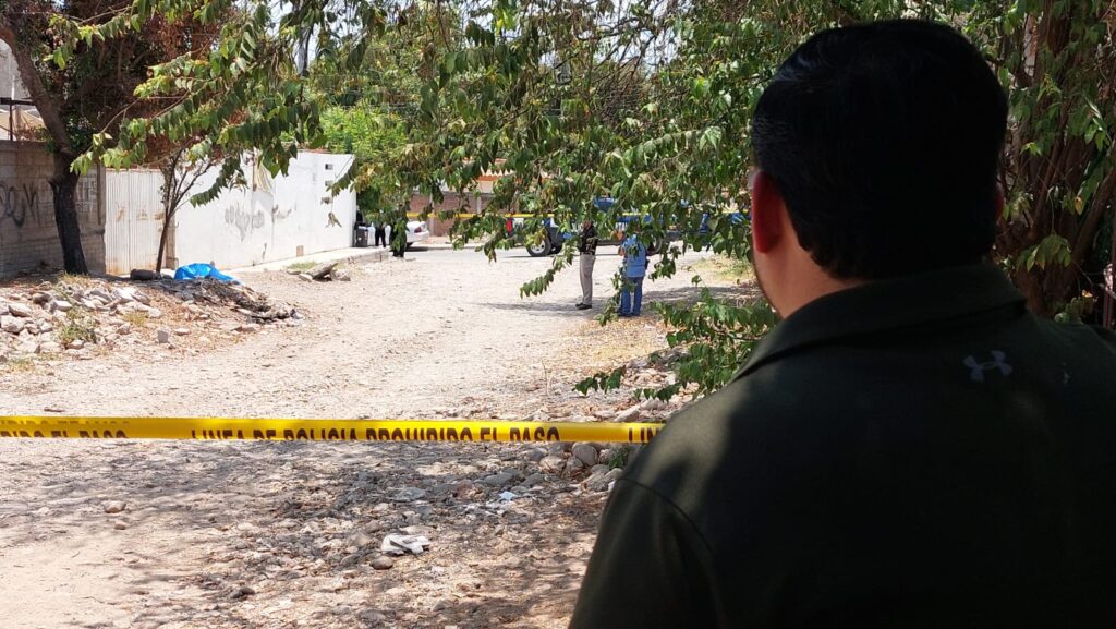 Agente estatal resguarda línea amarilla que delimita hallazgo de un hombre sin vida