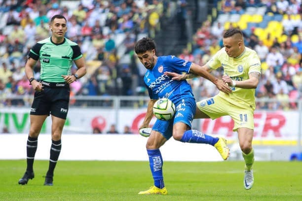 Una persona mirando a 2 más disputarse un balón en un campo de fútbol
