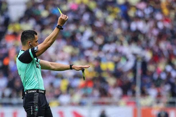 Una persona sacando una tarjeta amarilla en un campo de fútbol