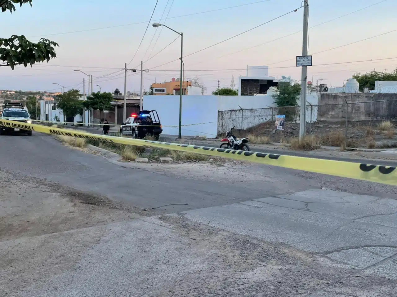 Área de un crimen delimitada con cinta amarilla, cuerpo de un hombre sin vida a un lado de una motocicleta