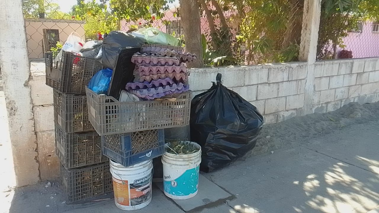 Jabas, cubetas y bolsa de basura sobre la banqueta