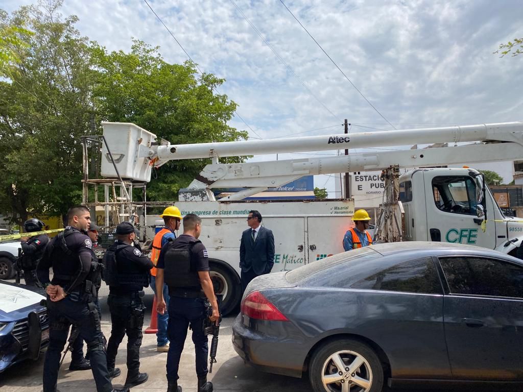 Policías y personal de la CFE platicando a un lado de una patrulla y del camión de la comisión de electricidad