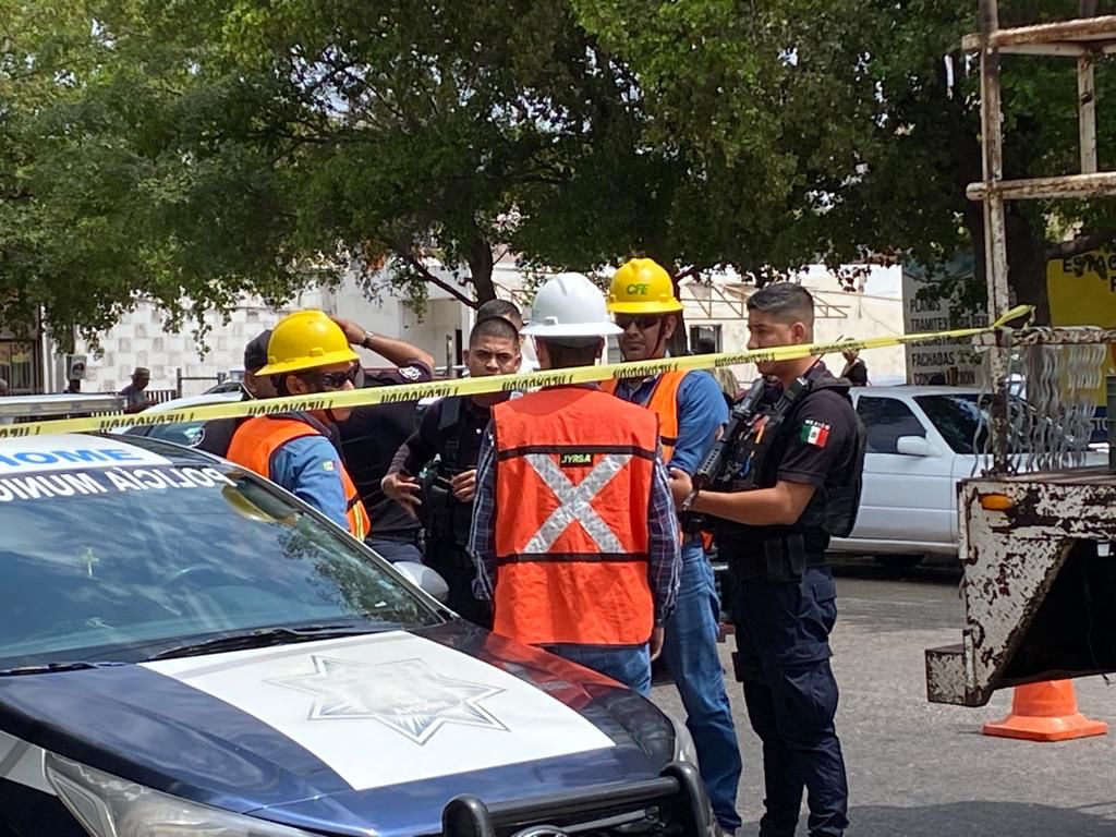 Policías y personal de la CFE platicando a un lado de una patrulla y del camión de la comisión de electricidad