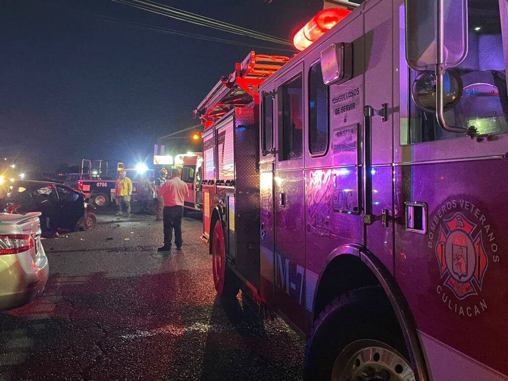 Camión de bomberos veteranos en primer plano al fondo personas involucradas en el accidente paramédicos y policías