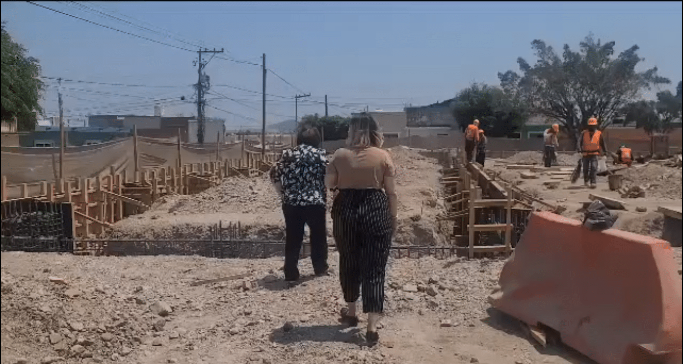 La funcionaria estatal acompañada de otra persona mientras supervisan obras en donde se encuentran algunos trabajadores realizando actividades