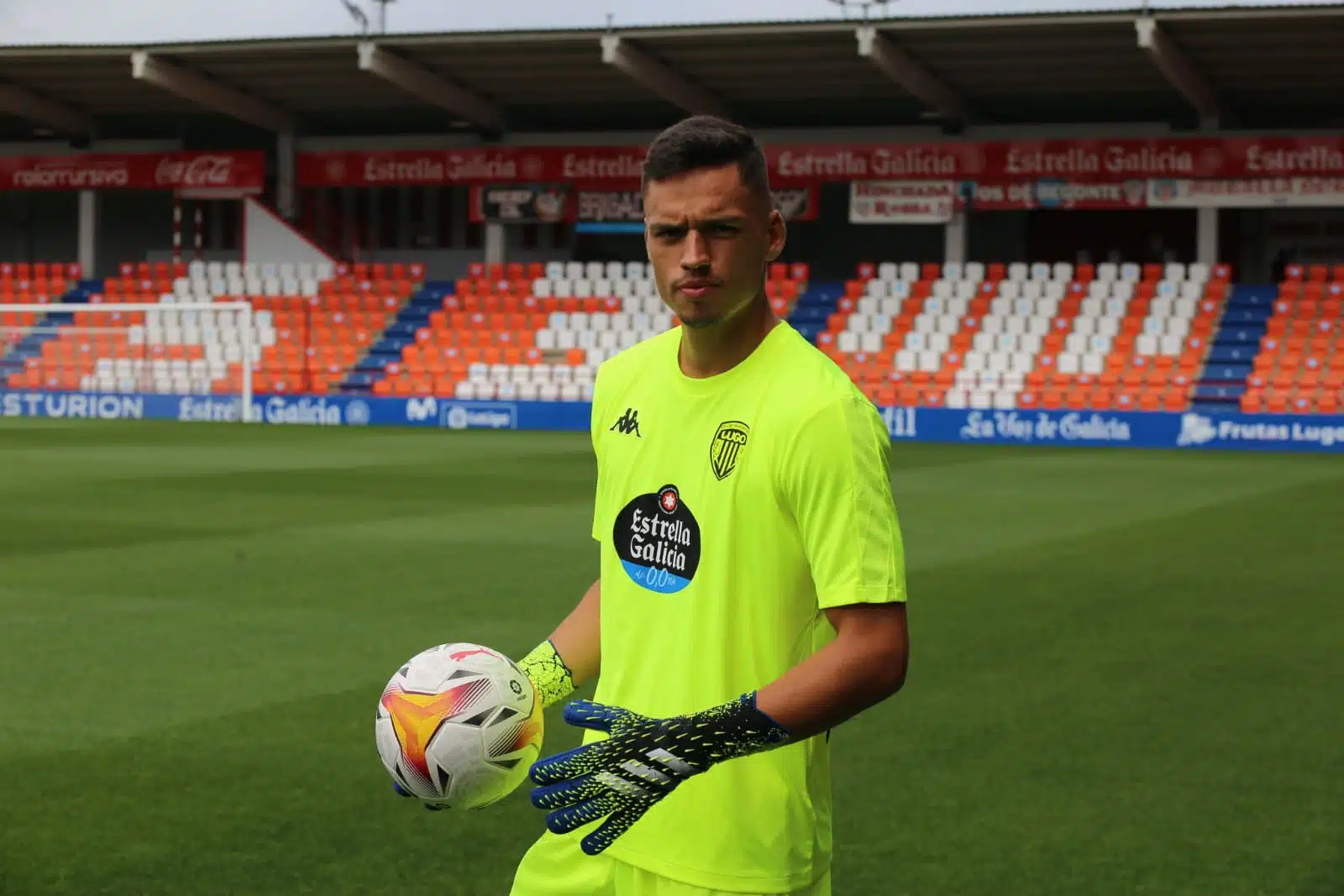 El futbolista español Óscar Whalley en el campo con una pelota y guantes portando su uniforme del equipo