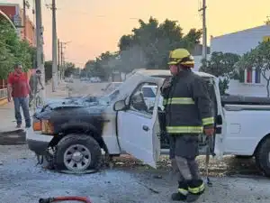 Bombero de Culiacán supervisa la camioneta tras extinguir el fuego originado por un cortocircuito en el motor de la unidad