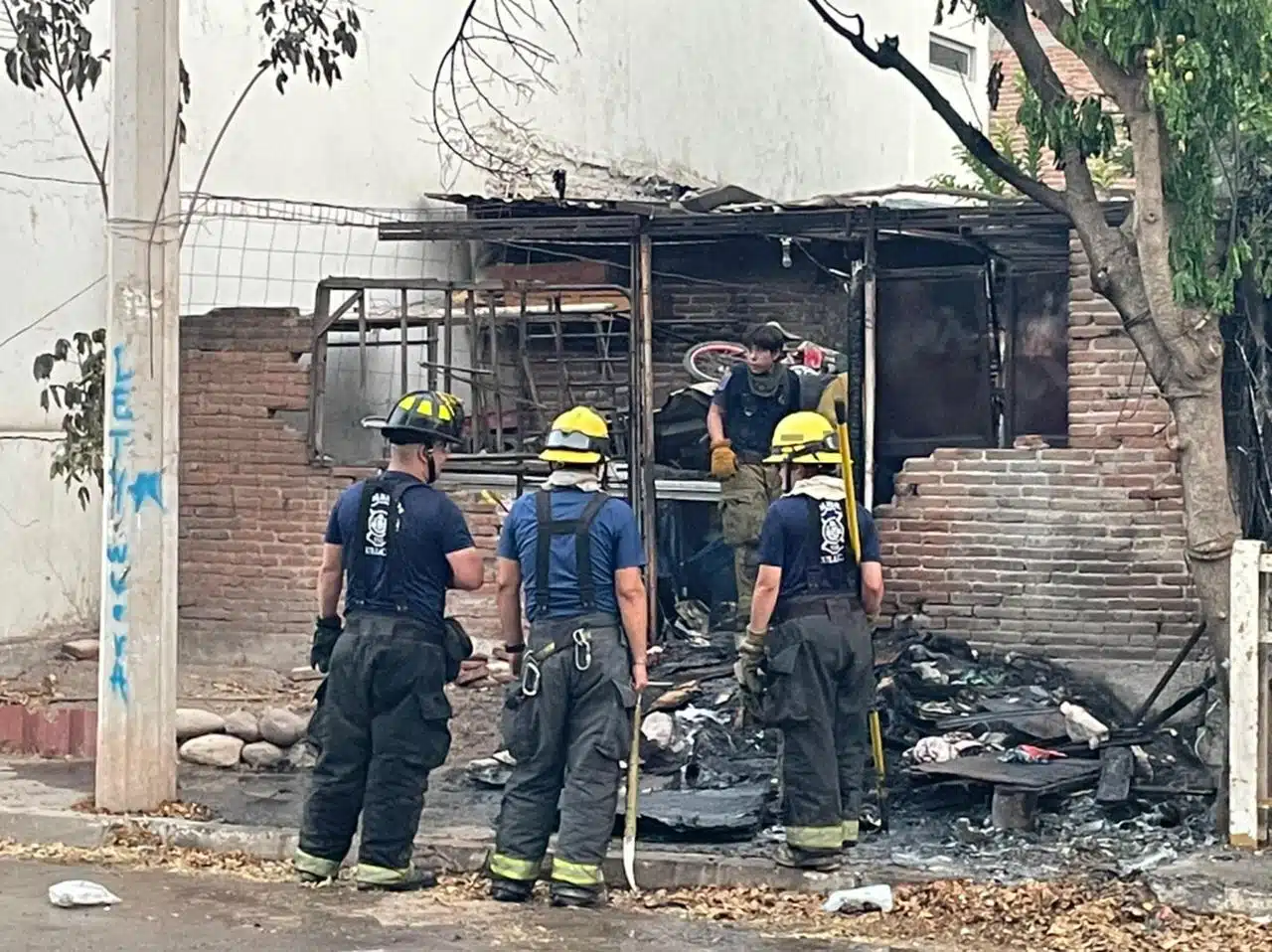 Bomberos parados mirando hacía la casa quemada