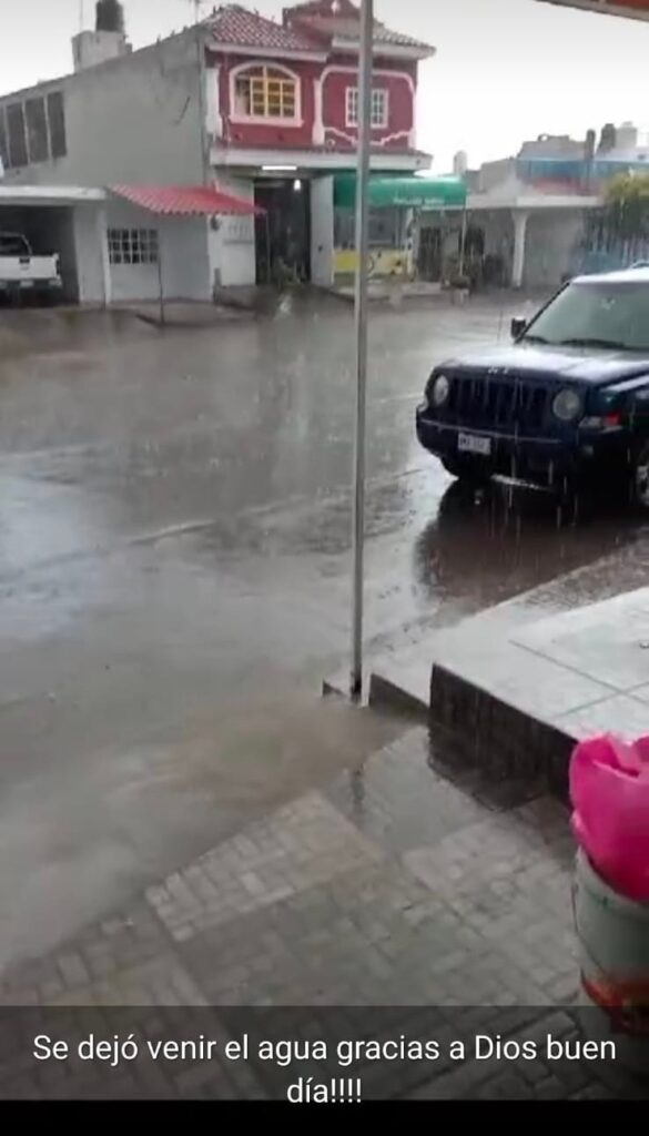 Lluvia, pavimento mojado, carros estacionados casas al fondo