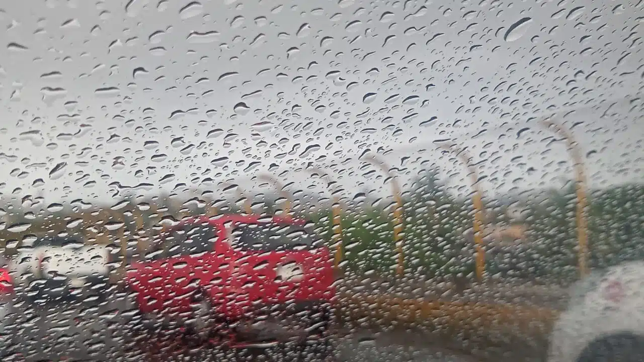 Gotas de lluvia en el parabrisas de un automóvil en plena carretera