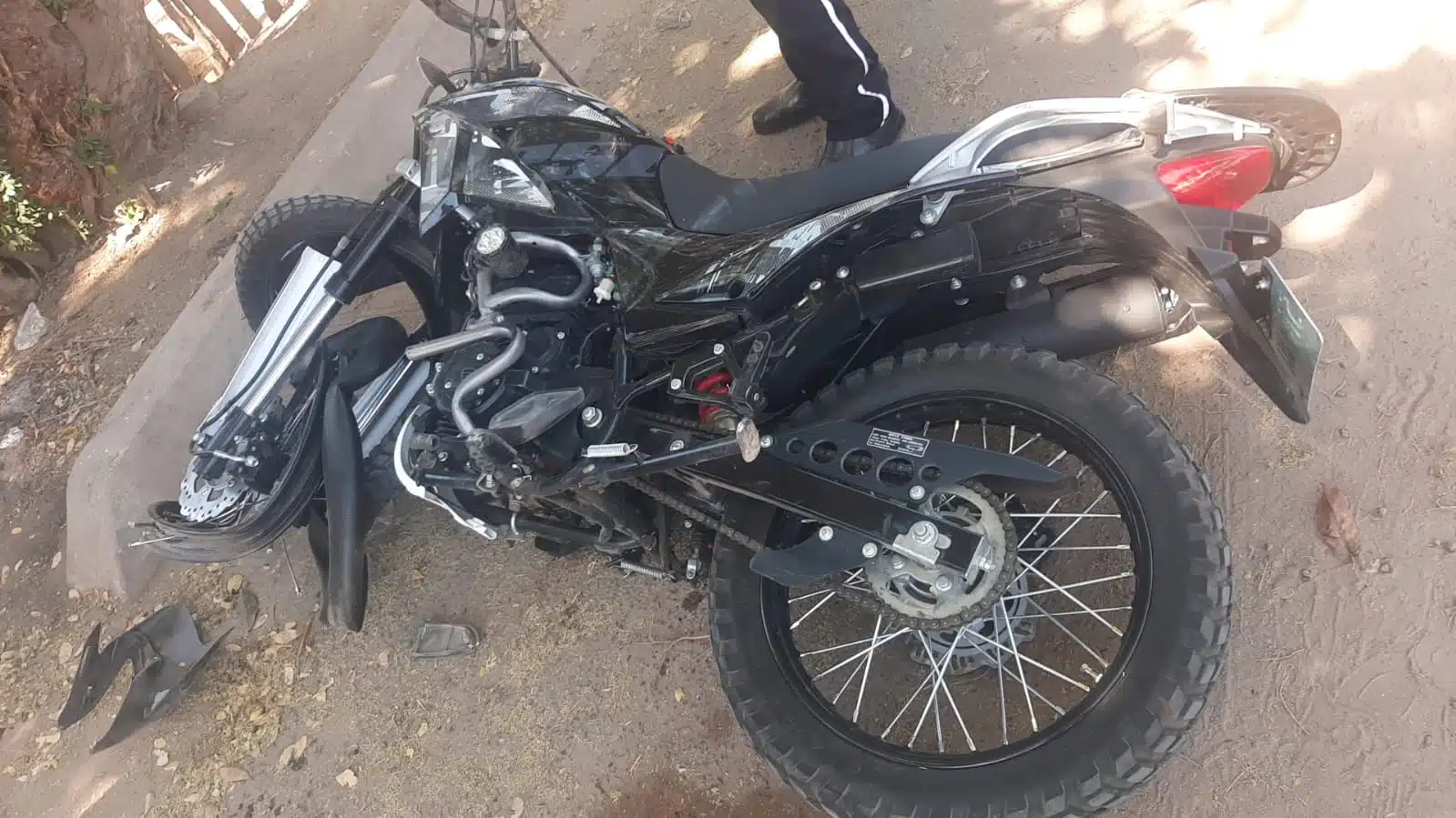 Motocicleta Itlaika, color negro, tirada en calle de tierra en Guasave tras accidente