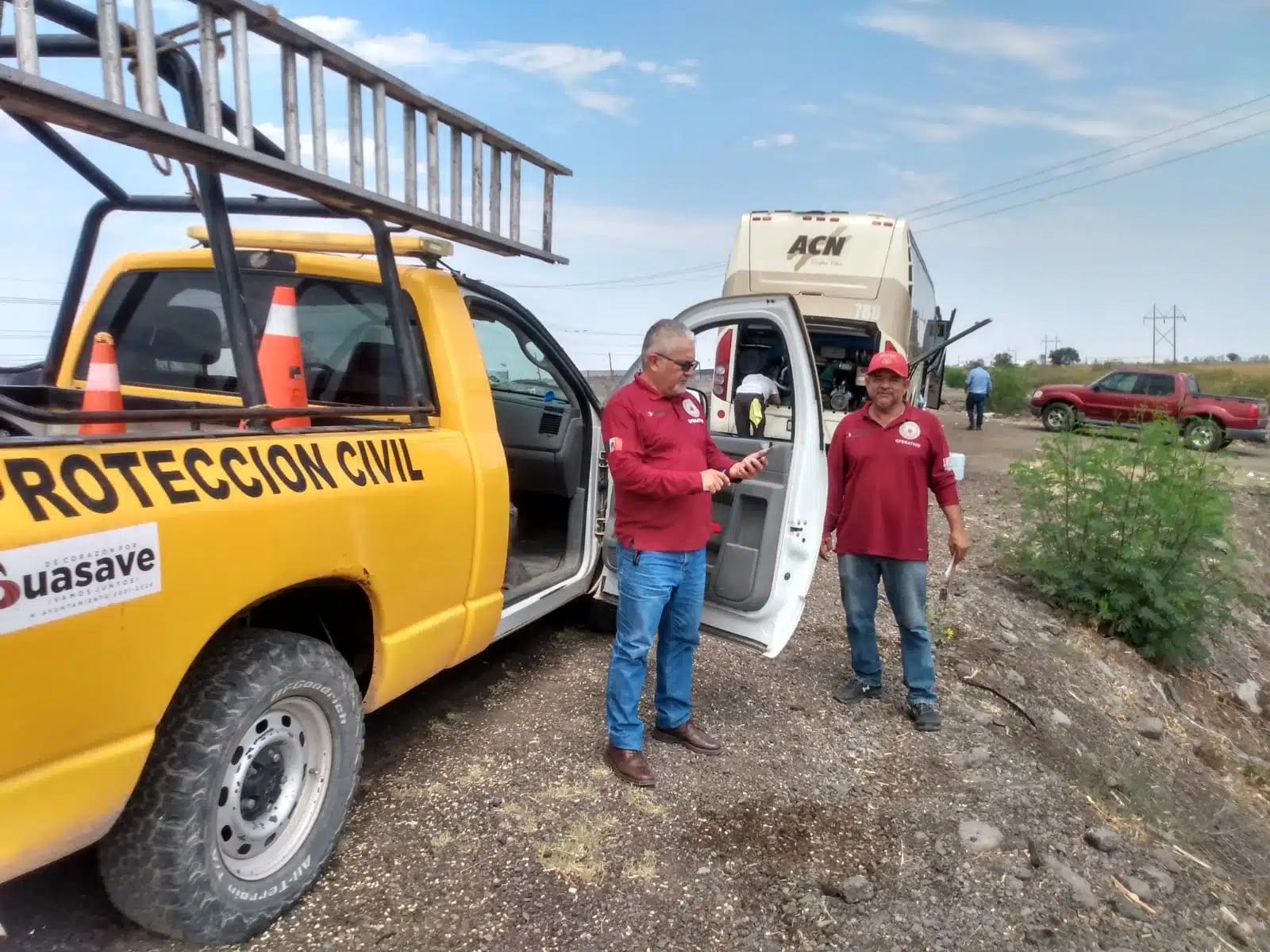 Camioneta y camión parados sobre el acotamiento de la carretera y 2 personas sobre la tierra