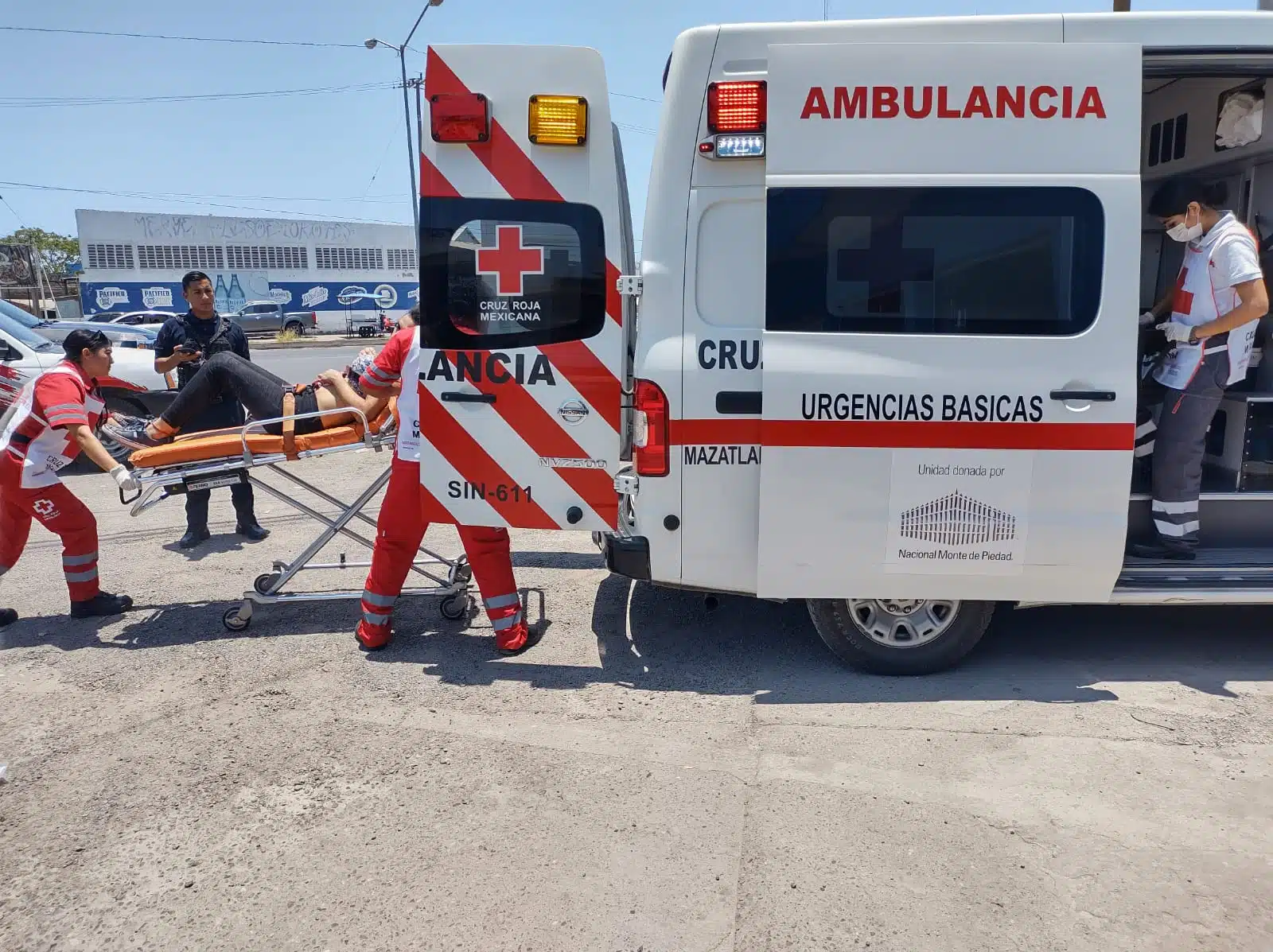 Personal de Cruz Roja transportando en camilla a una persona herida hacia la ambulancia