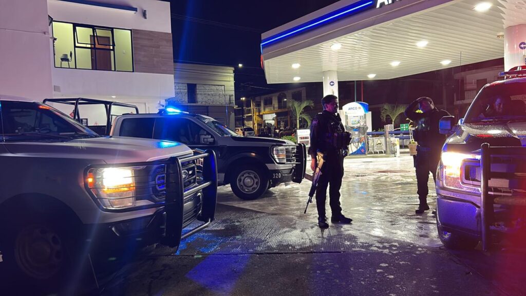 Agentes policiacos junto a sus vehículos en una gasolinera