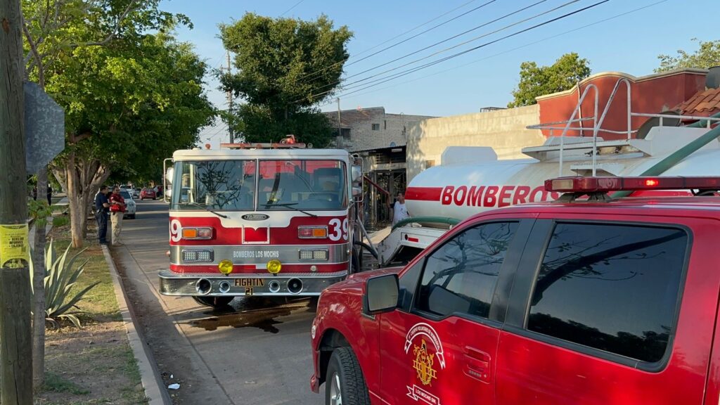 Camión de Bomberos estacionado en una calle frente a vehículo personal rojo