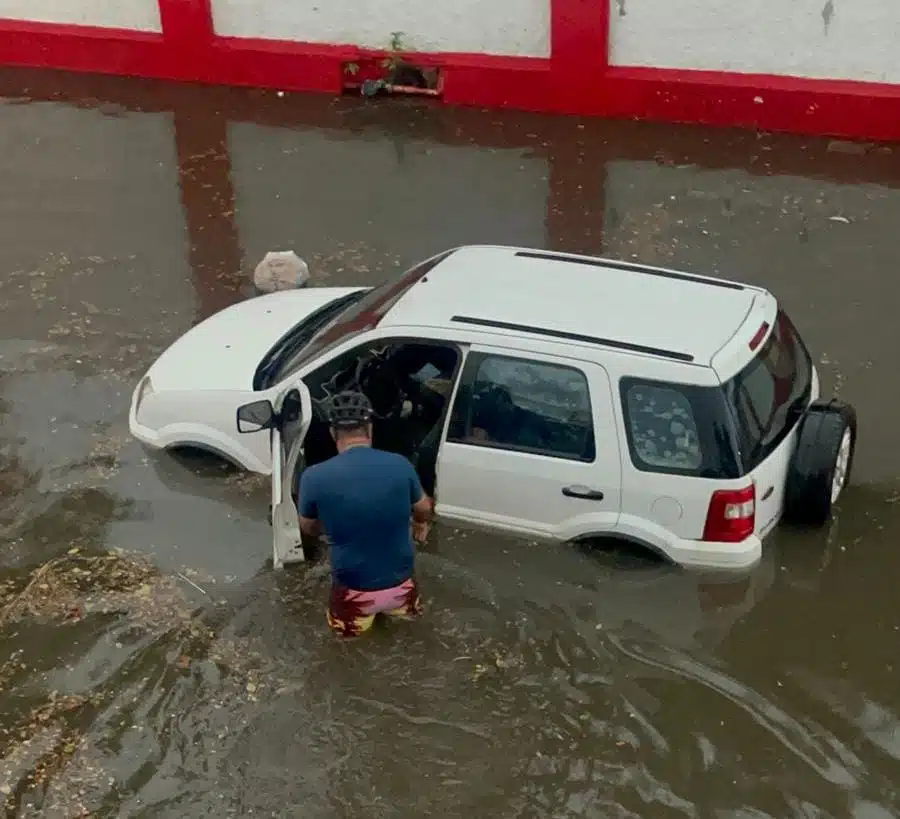 Persona ingresando a su vehículo por una calle sumamente inundada