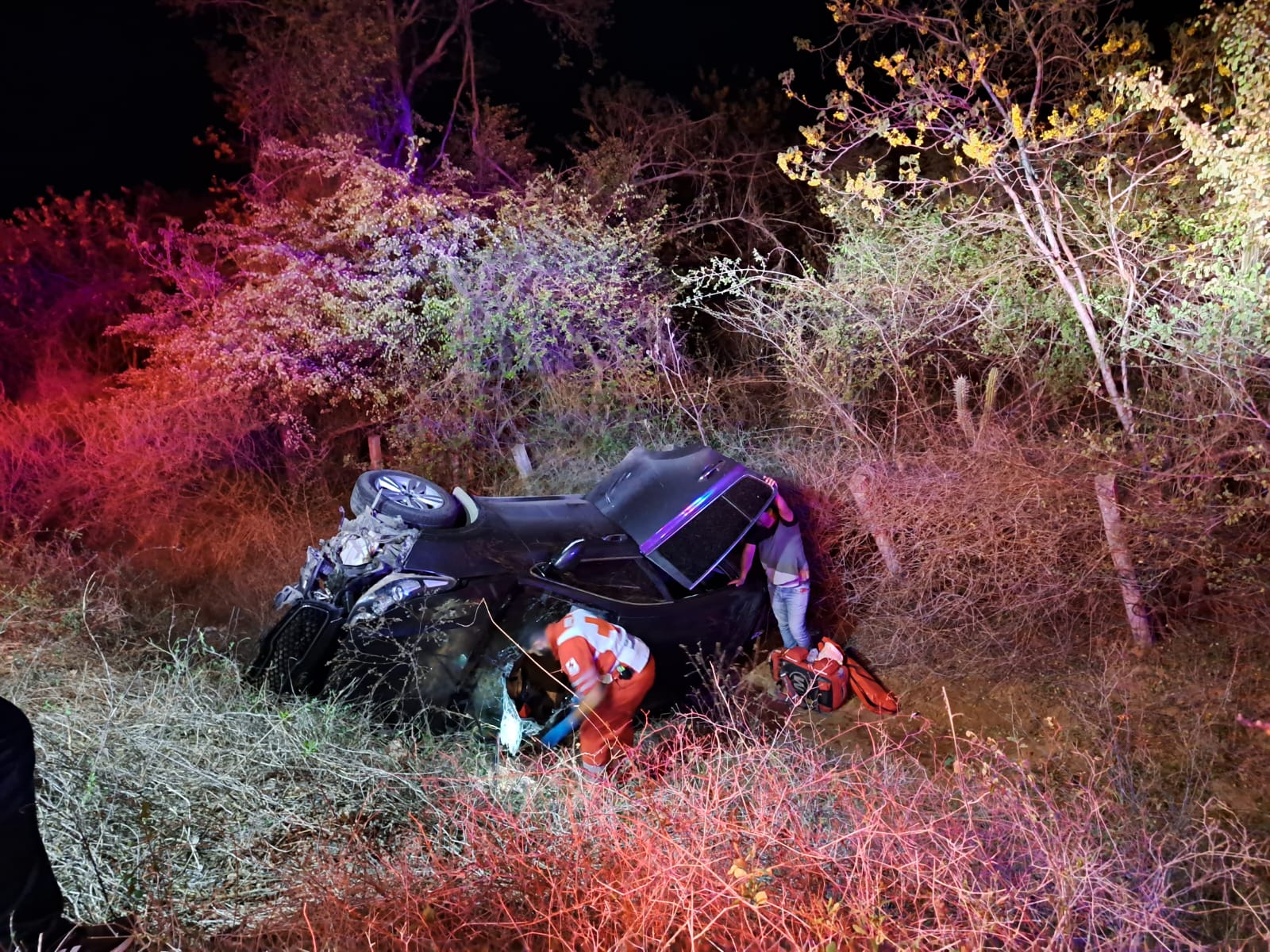 Personal de Cruz Roja auxiliando a personas a bordo de camioneta volcada
