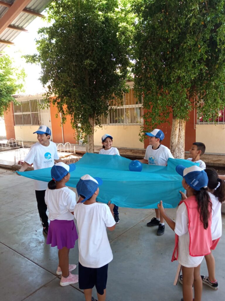 Niños realizando una actividad con una sábana y una pelota de color azul