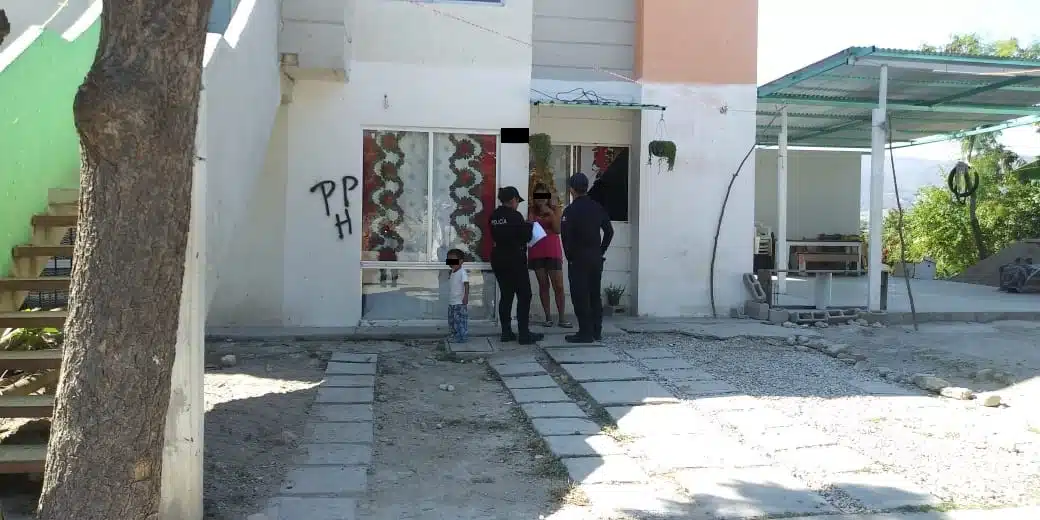 Agentes de policía interrogando a una madre de familia afuera de una vivienda