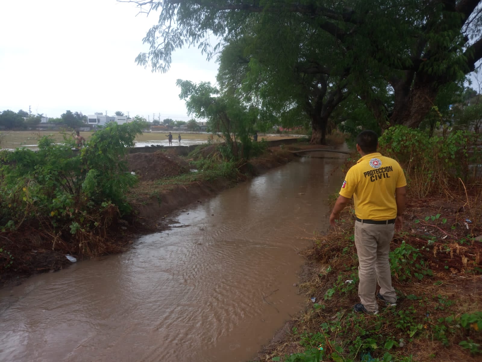 Personal de Protección Civil junto a un canal