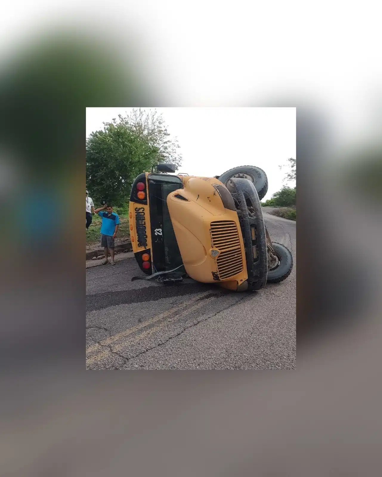 Un camión de color amarillo volcado sobre la carretera y a un lado una persona