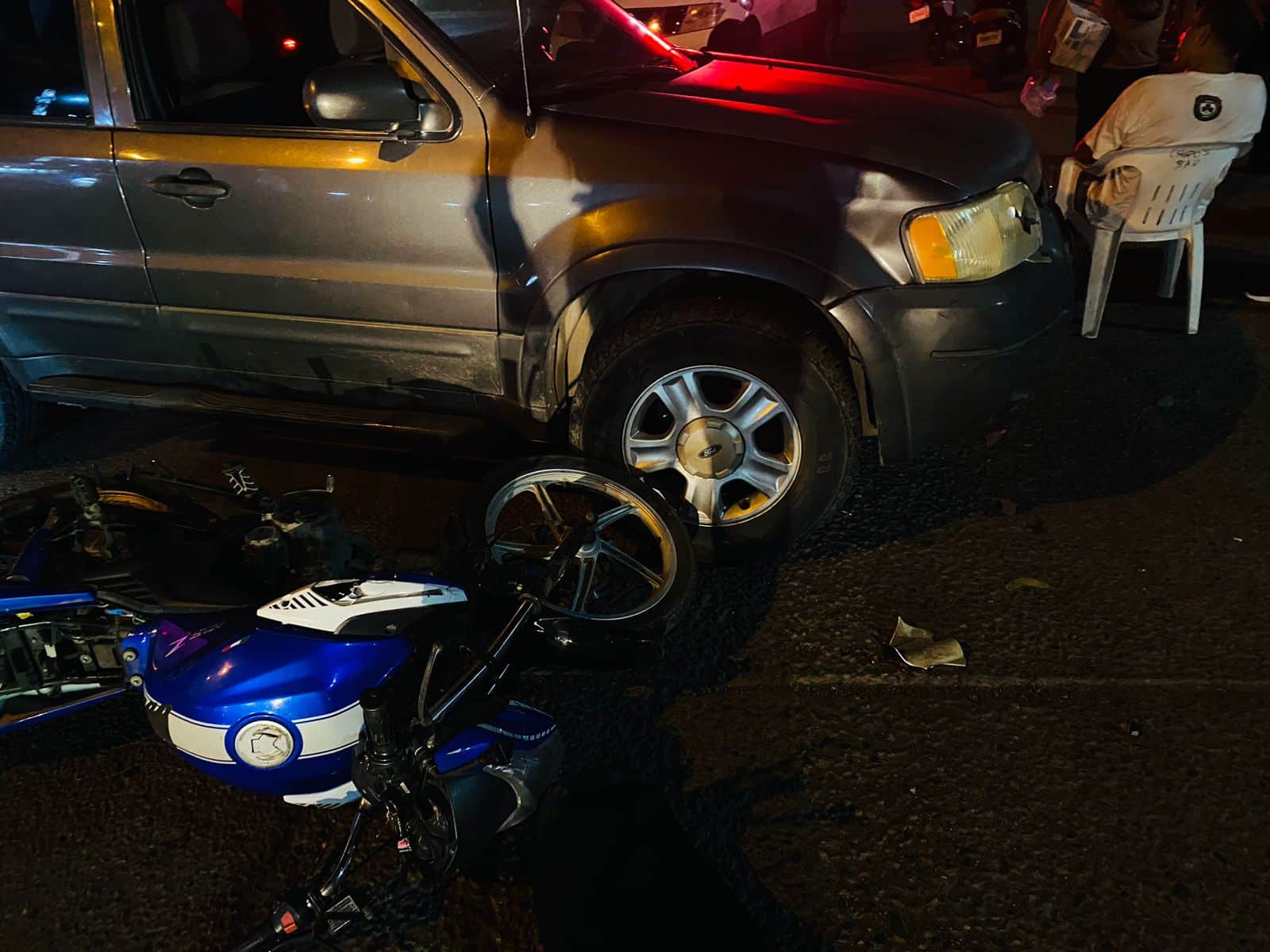 Una motocicleta sobre el suelo y a un lado una camioneta