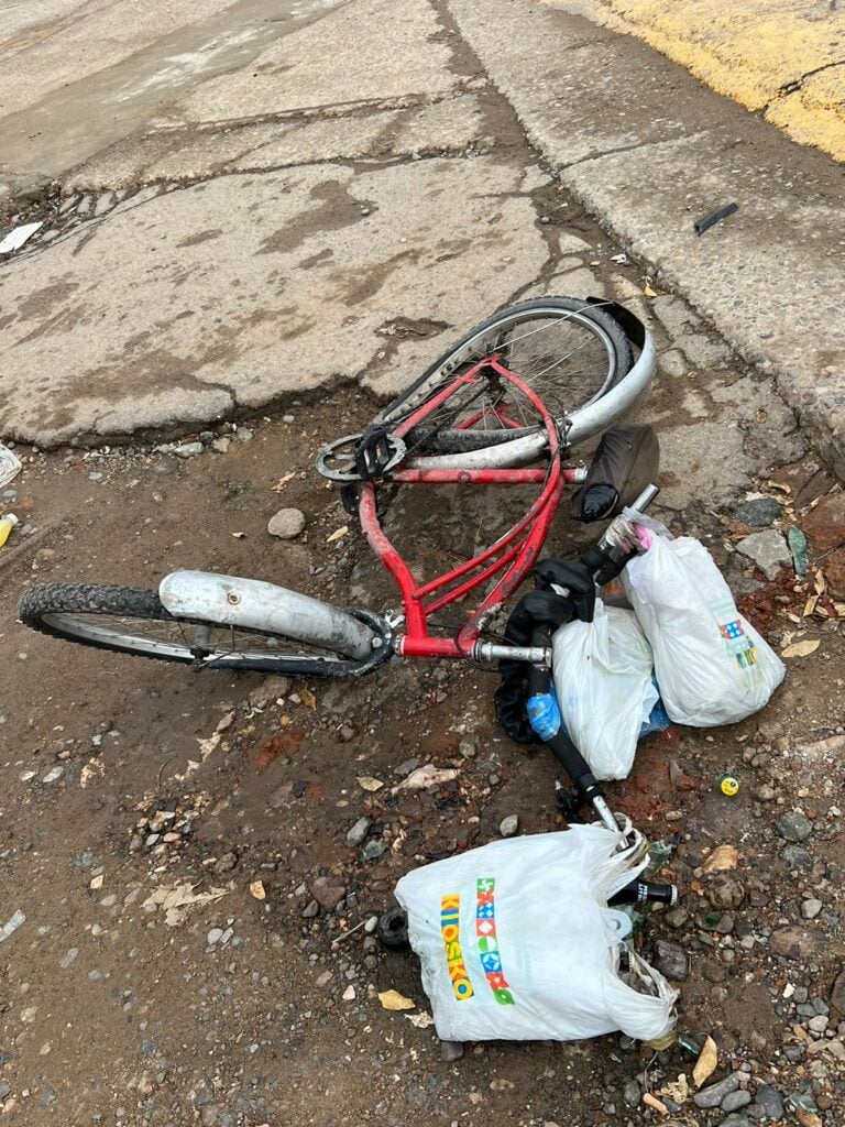 Una bicicleta con bolsas en el piso arrollada