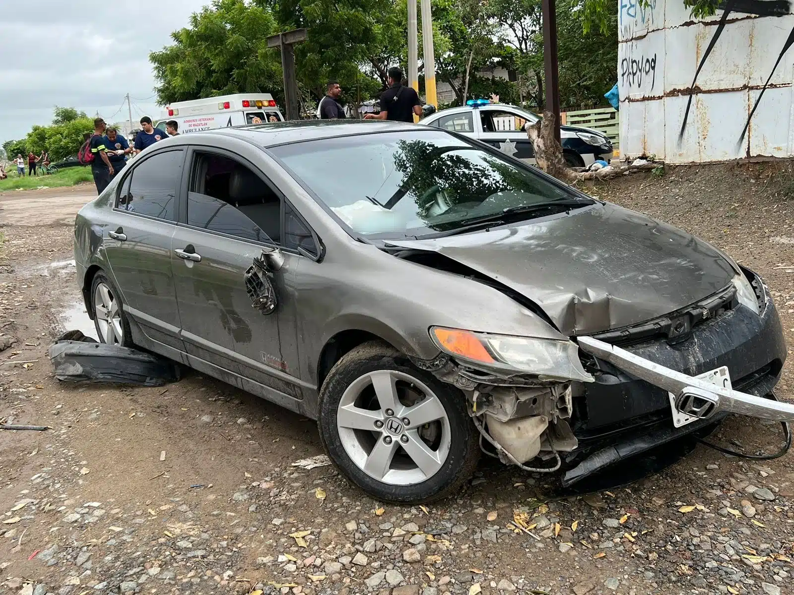 Un carro gris obscuro chocado del frente, al fondo personas