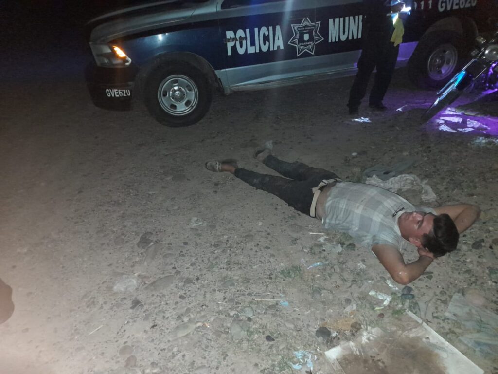 Una persona en el suelo y una camioneta estacionada de la policía