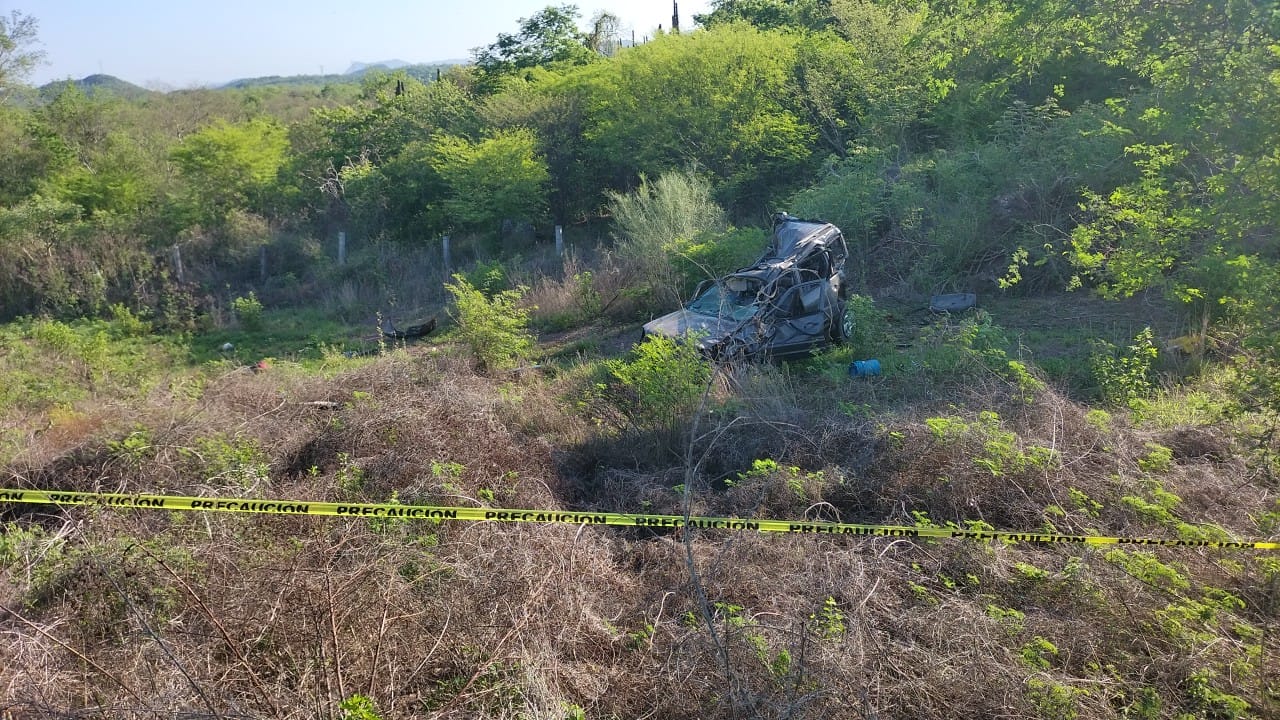 Una camioneta chocada por una volcadura, ramas y cinta amarilla delimitando el área