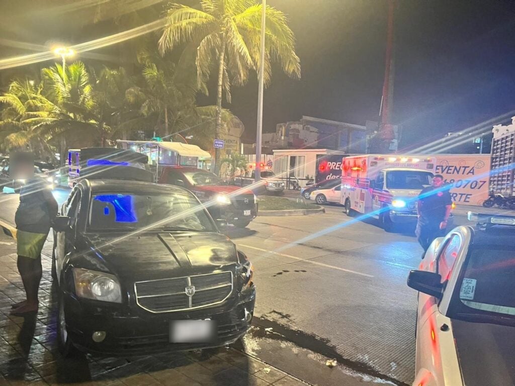 Una camioneta color negra, a un lado de ella una persona y al fondo más carros