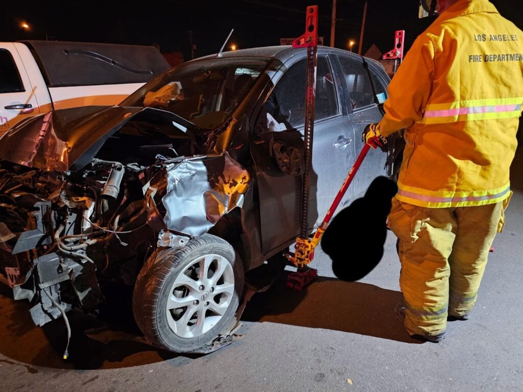 Auto March destrozado del frente y un elementoi de Bomberos haciendo maniobras