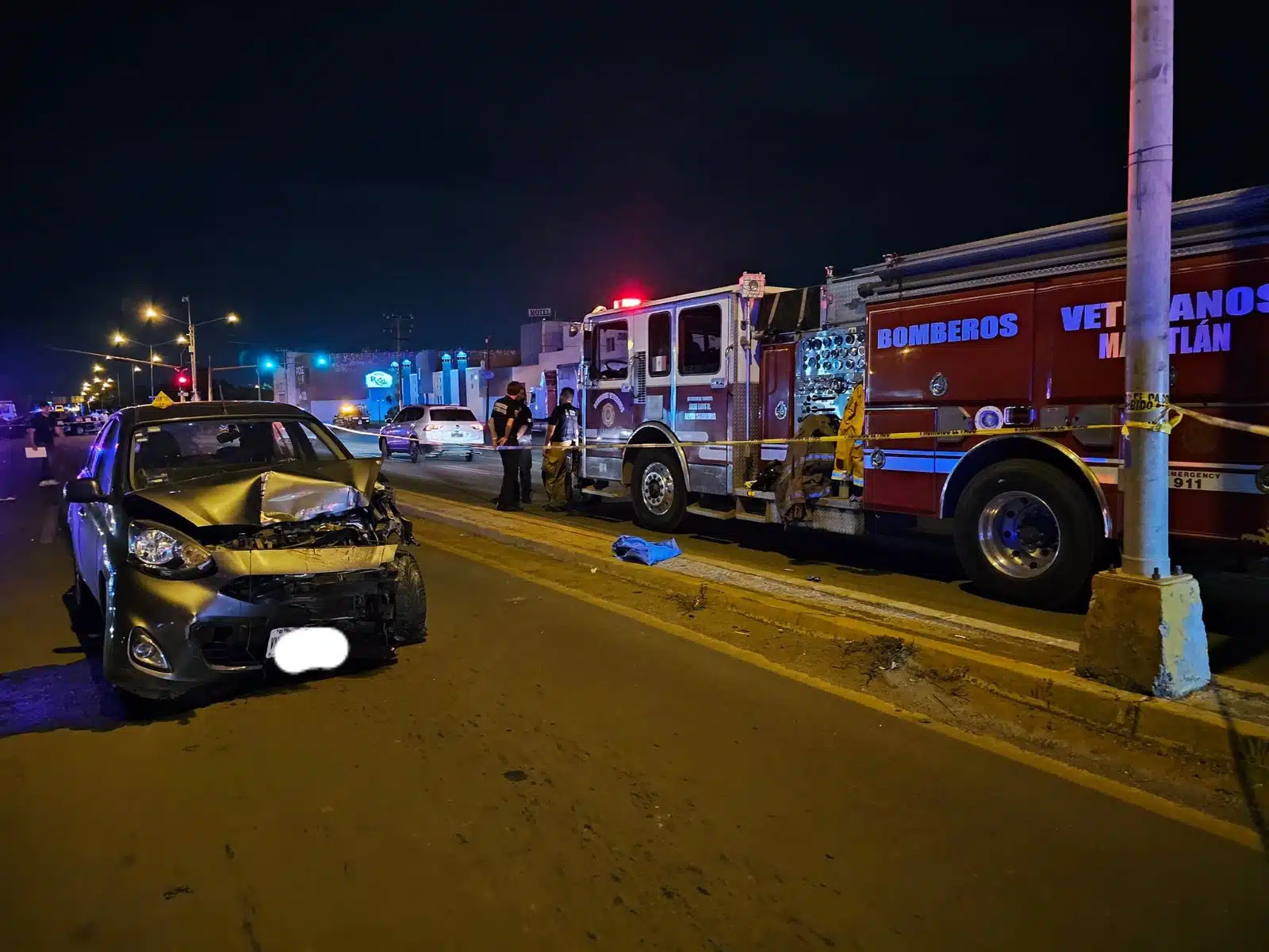 Auto March destrozado en medio de la calle tras accidente. Carro de Bomberos del otro lado de la calle