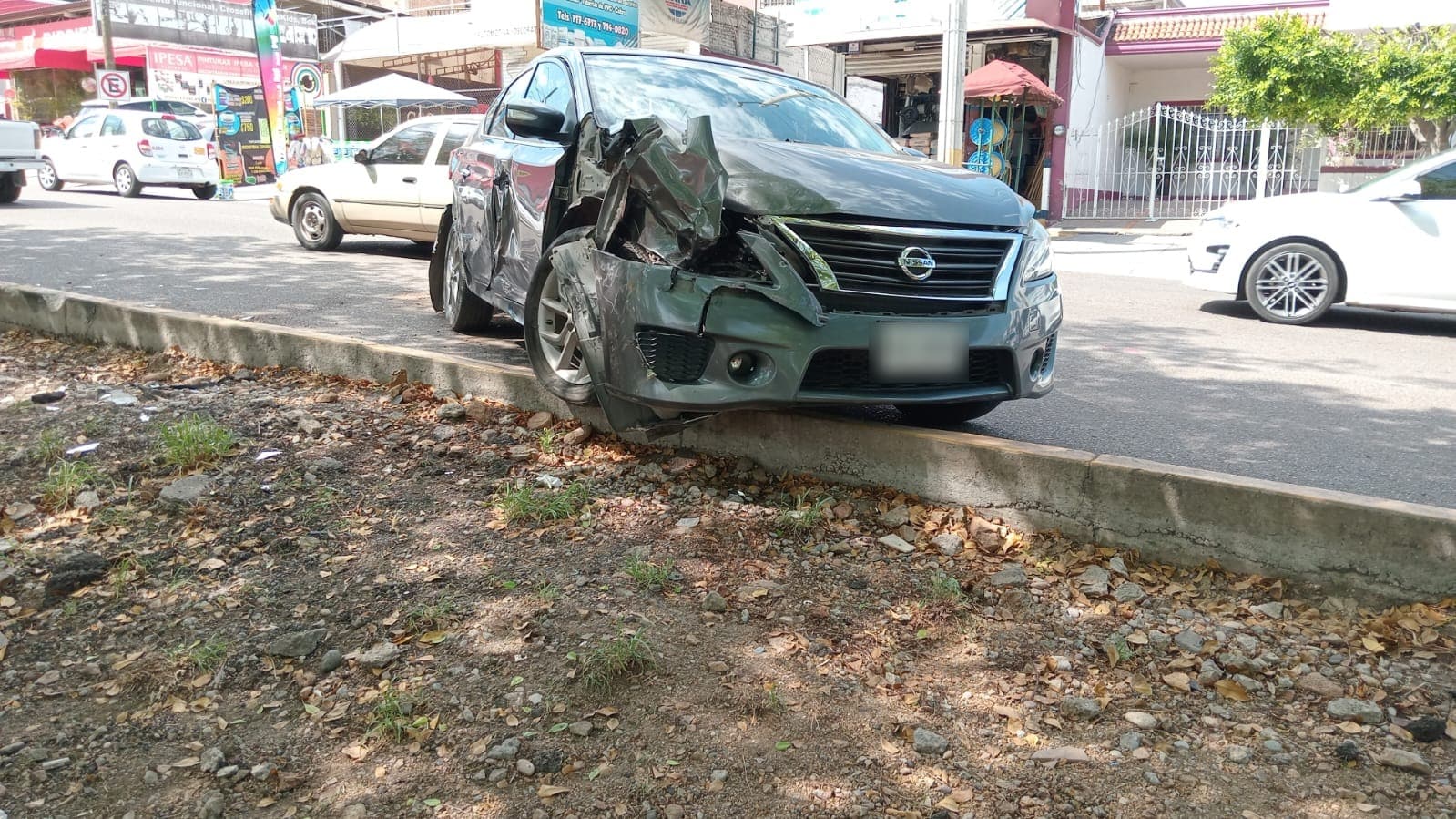 Un carro chocado, casas y carros al fondo