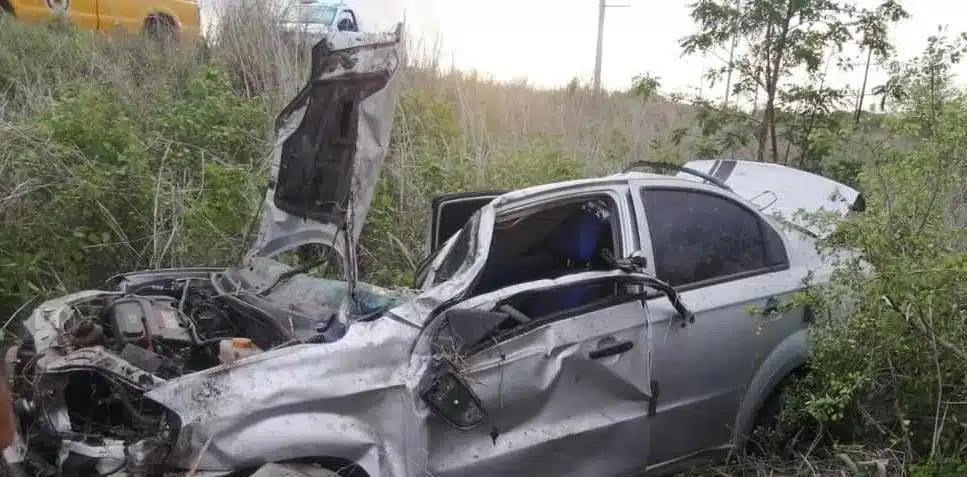 Un carro chocado por una volcadura y arbustos