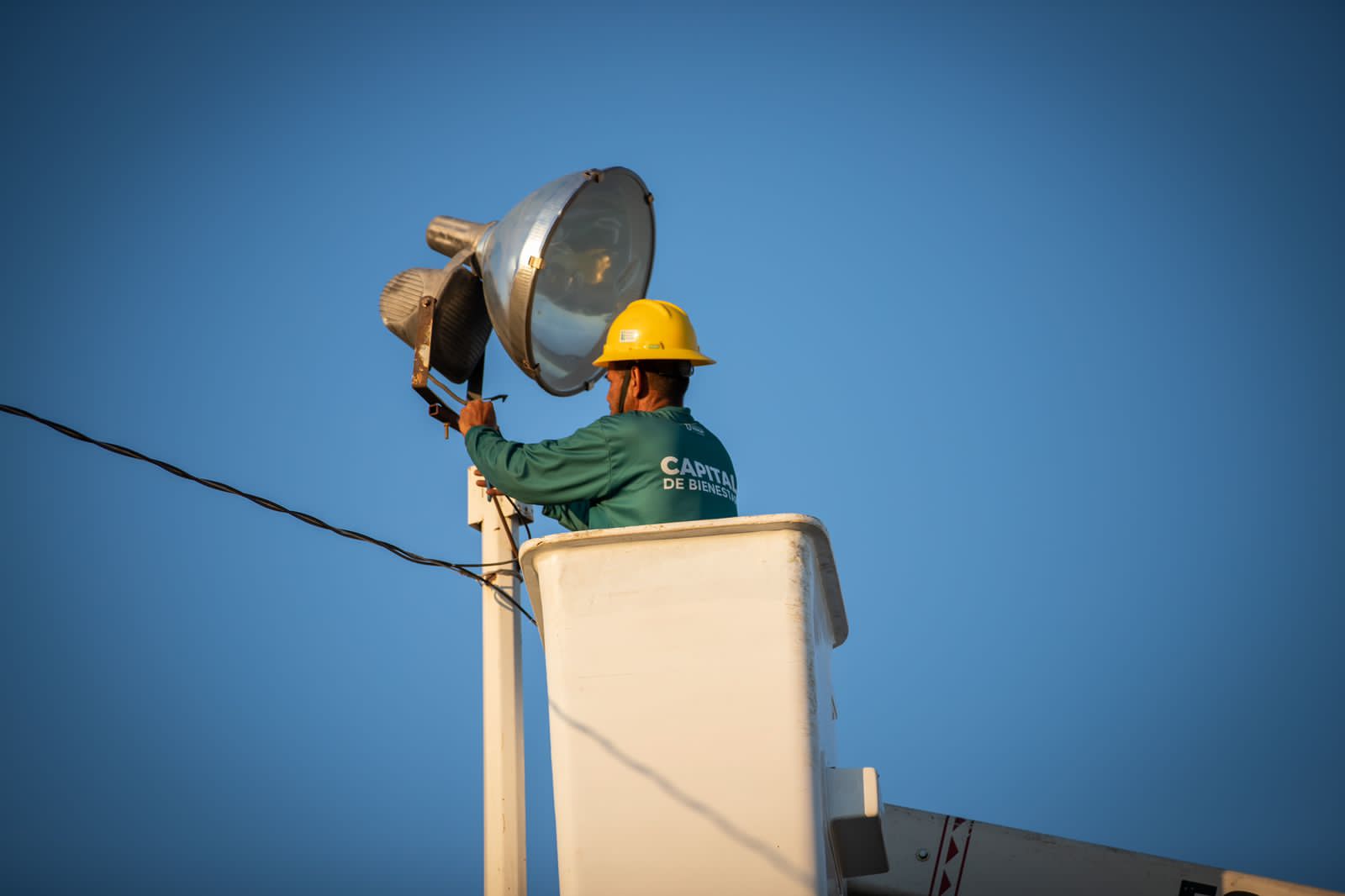 Una persona en una caja, un poste de luz, cable y el cielo
