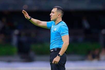 Una persona con una playera color azul y la mano levantada, y relojes en las manos