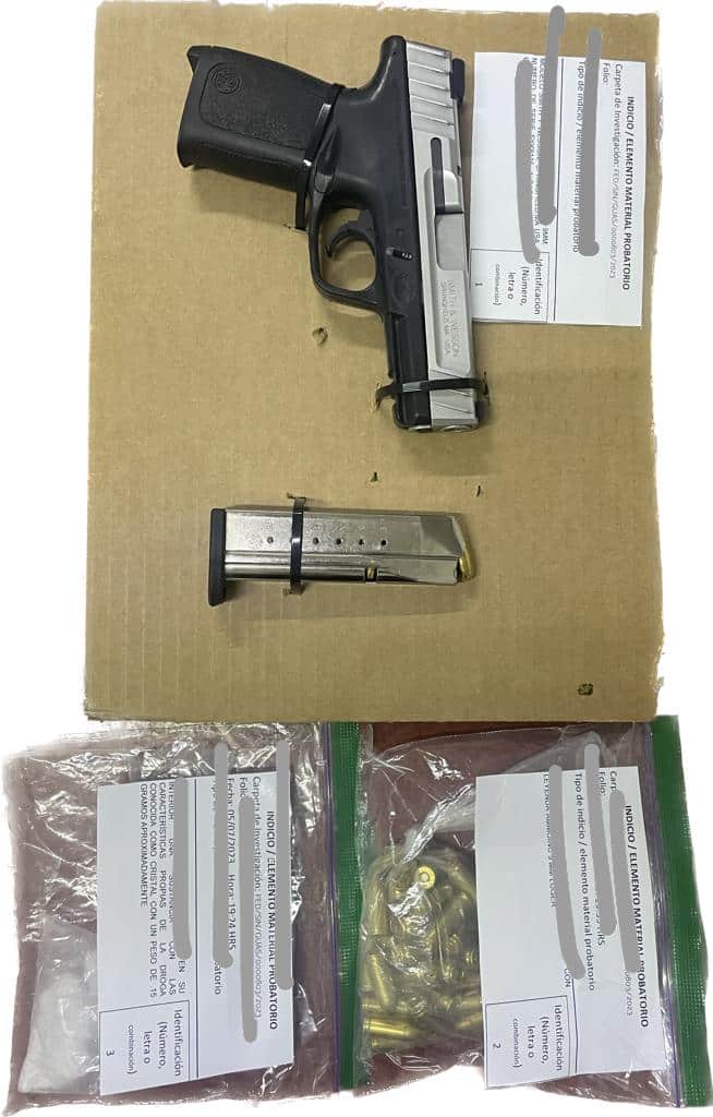 Una pistola y un cartucho en un pedazo de cartón, y al lado dos bolsas, 3 papeles