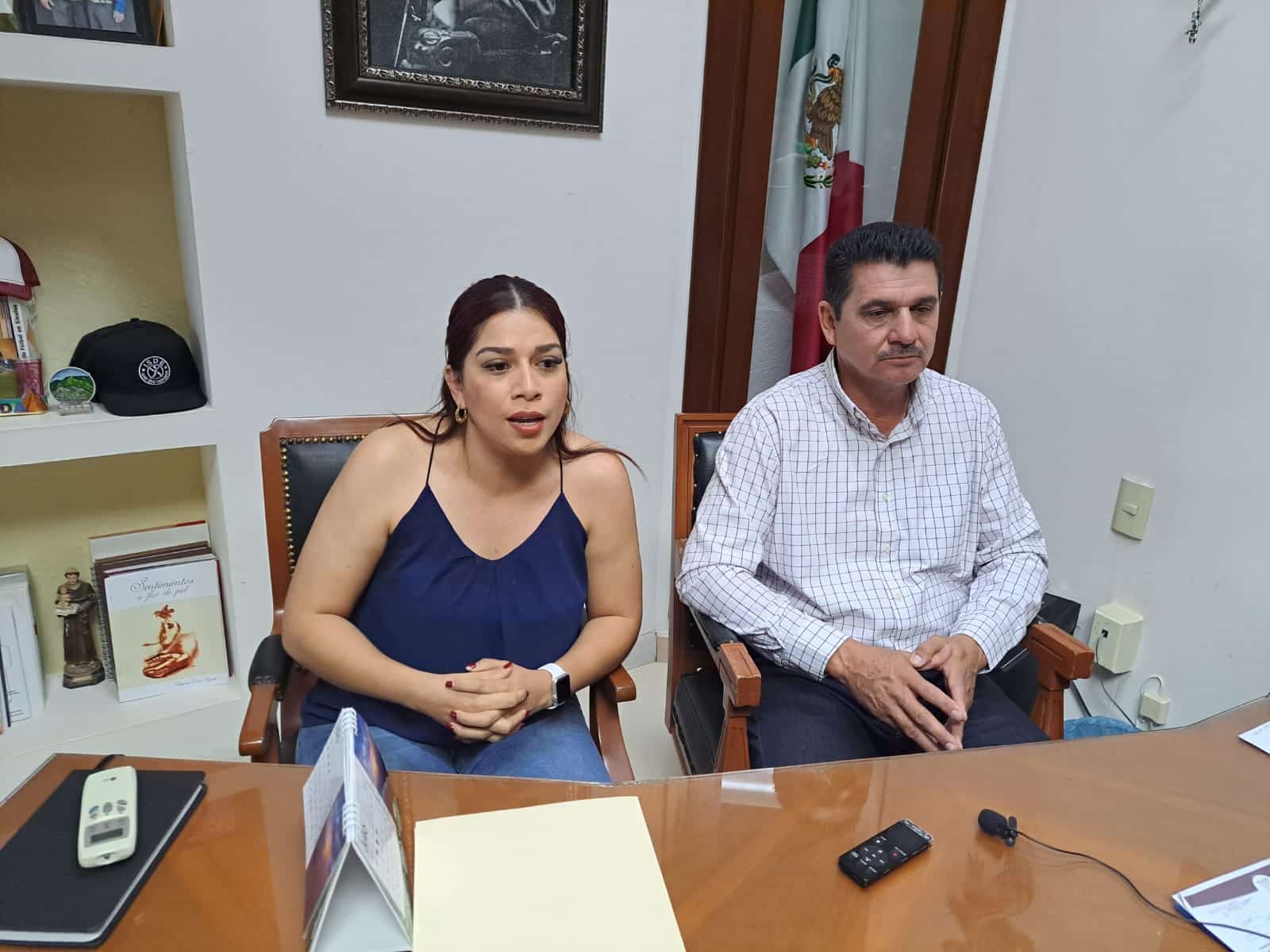 Dos personas sentadas frente a un escritorio con carpetas