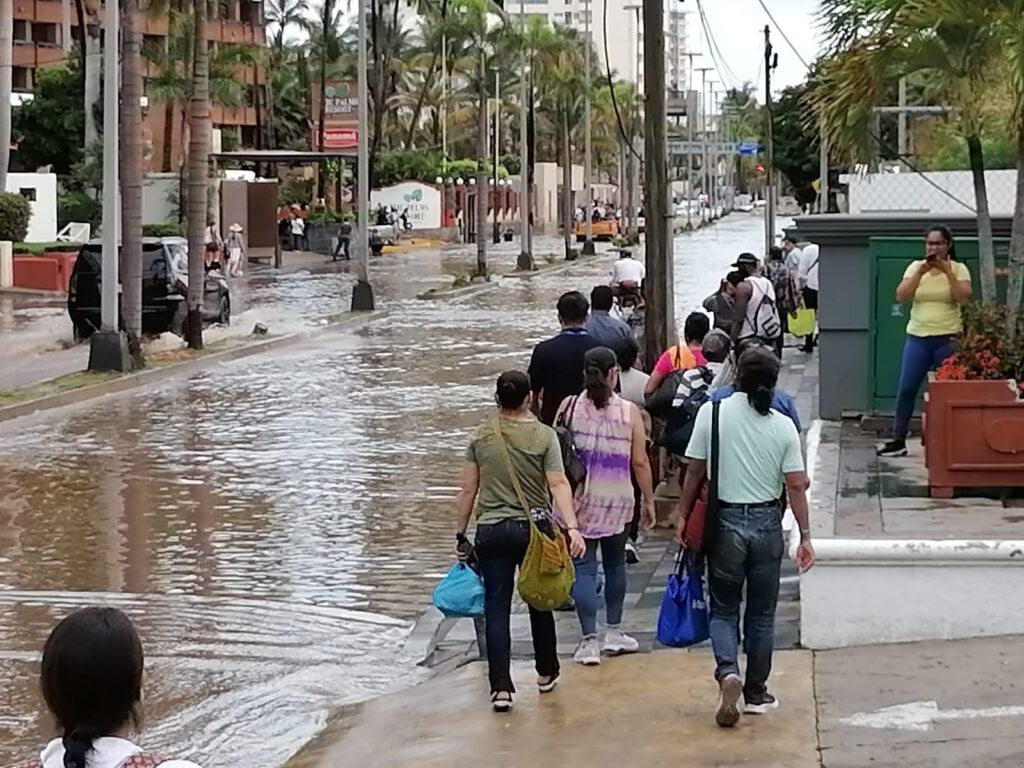 Calle inundada de agua y gente caminando sobre una banqueta