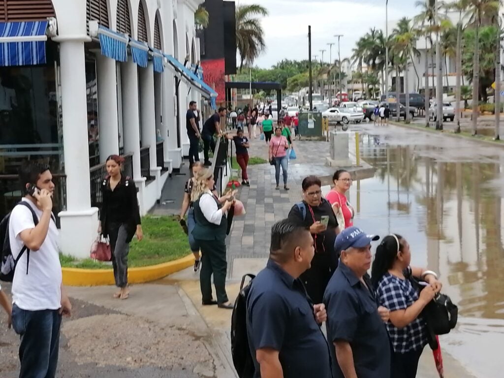 Calle inundada de agua y gente caminando sobre una banqueta