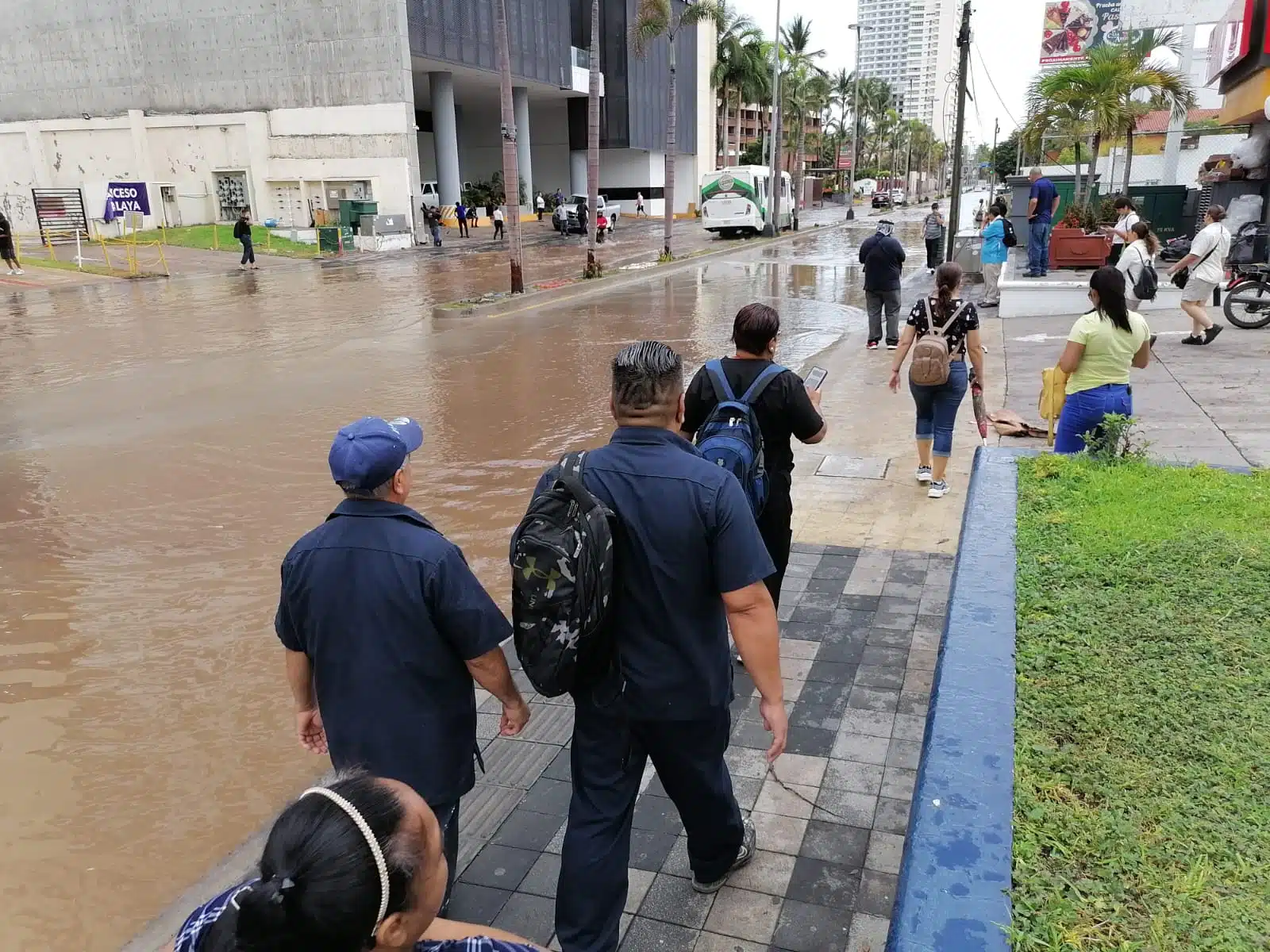 Calle inundada de agua y gente caminando sobre una banqueta