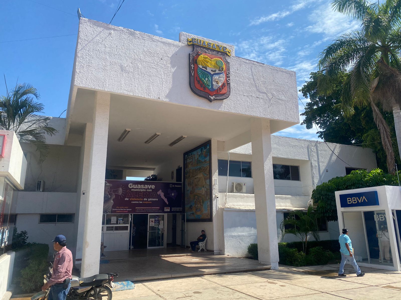Un edificio con el logotipo del municipio de Guasave y árboles