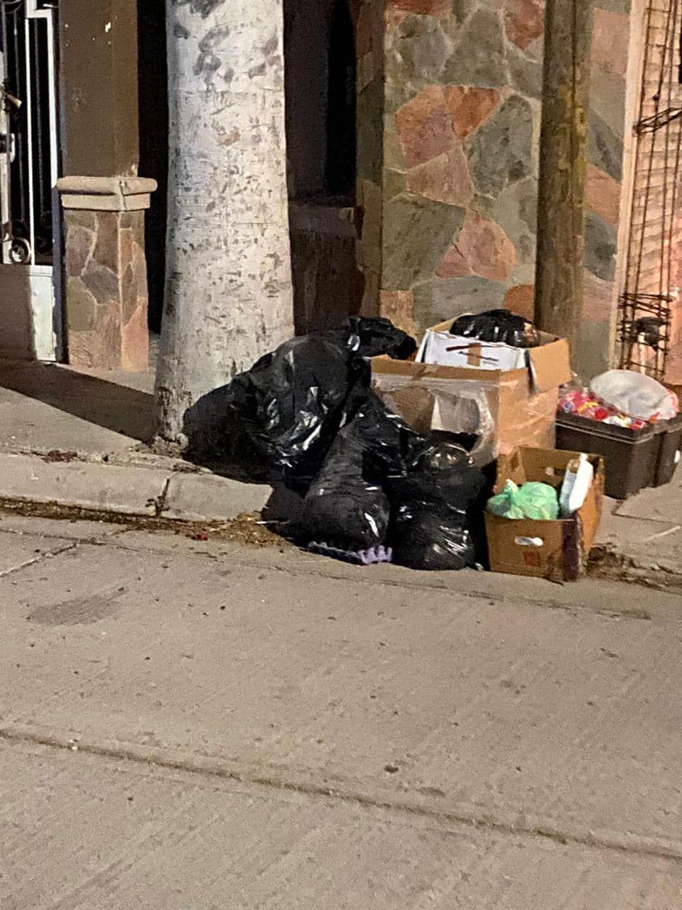 Cartones, jabas y bolsas de basura sobre la banqueta